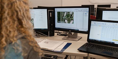 Female student works in front of multiple computer monitors showing Ag yields